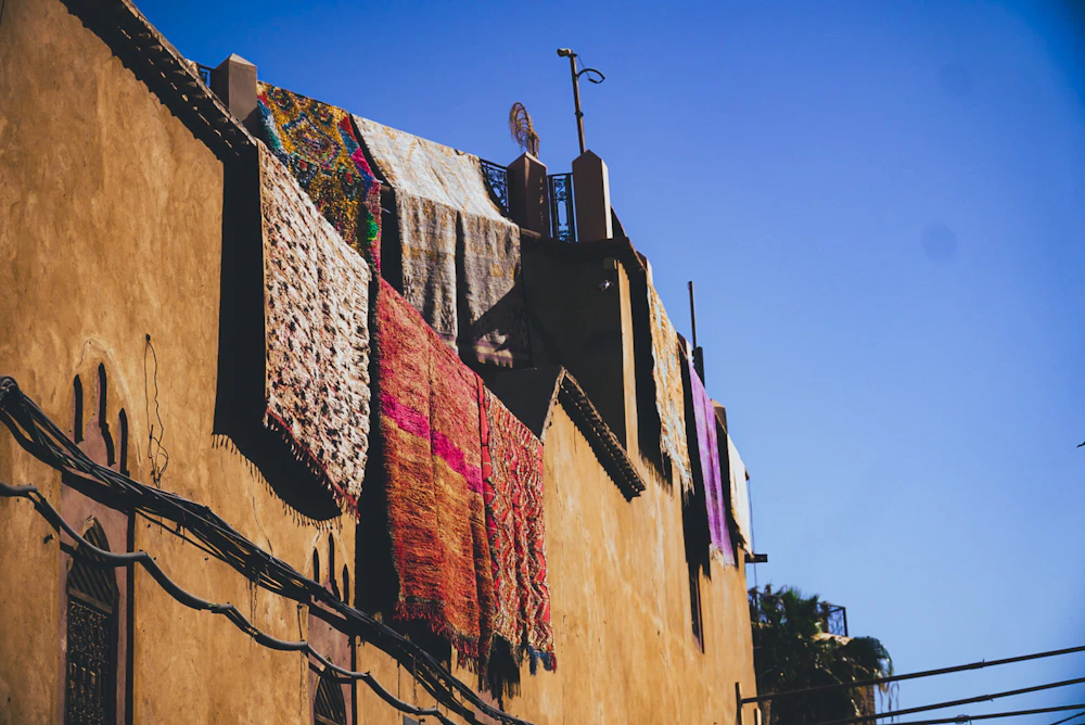 Handwoven textiles displayed across traditional Moroccan architecture