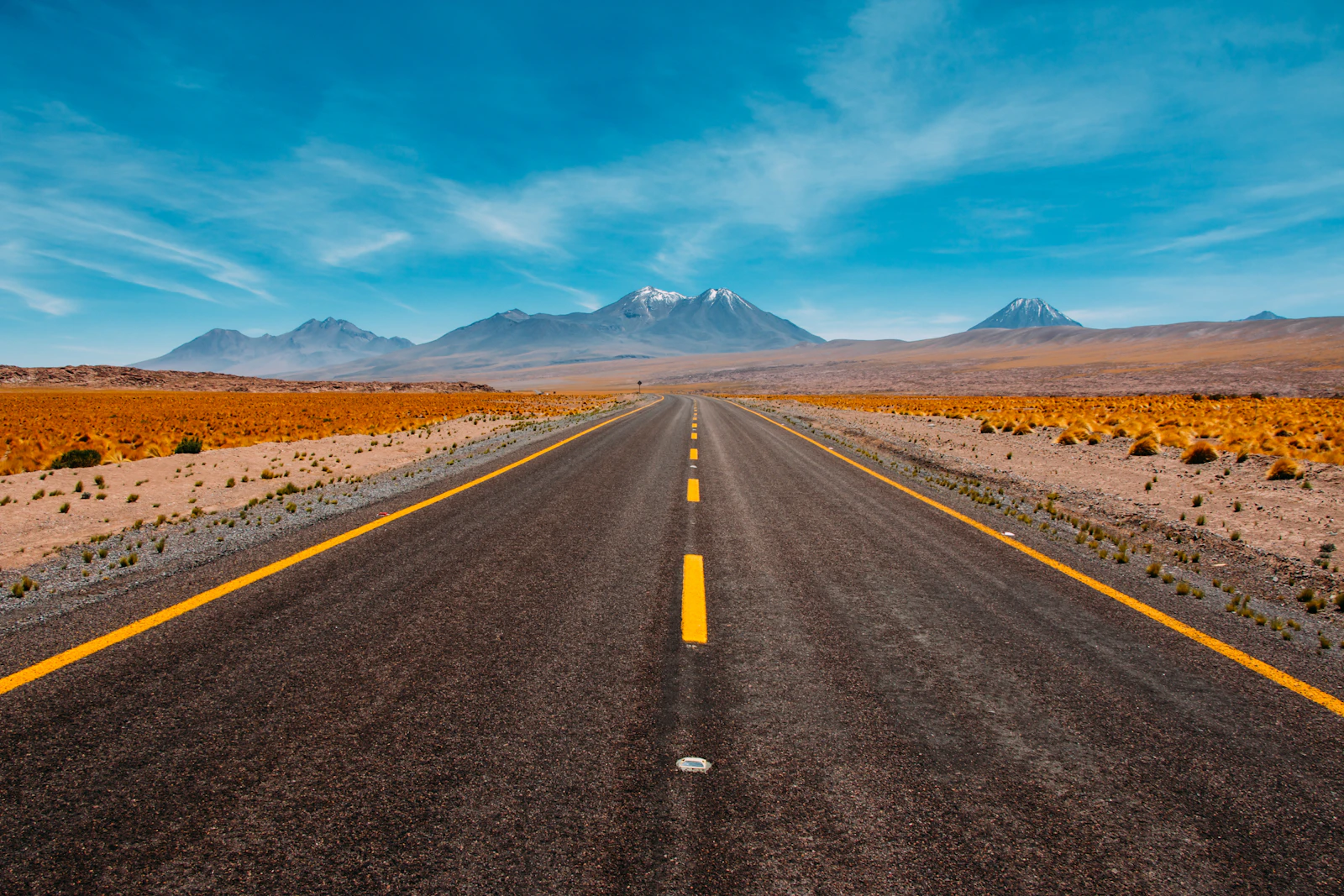Open desert road leading toward distant mountain peaks